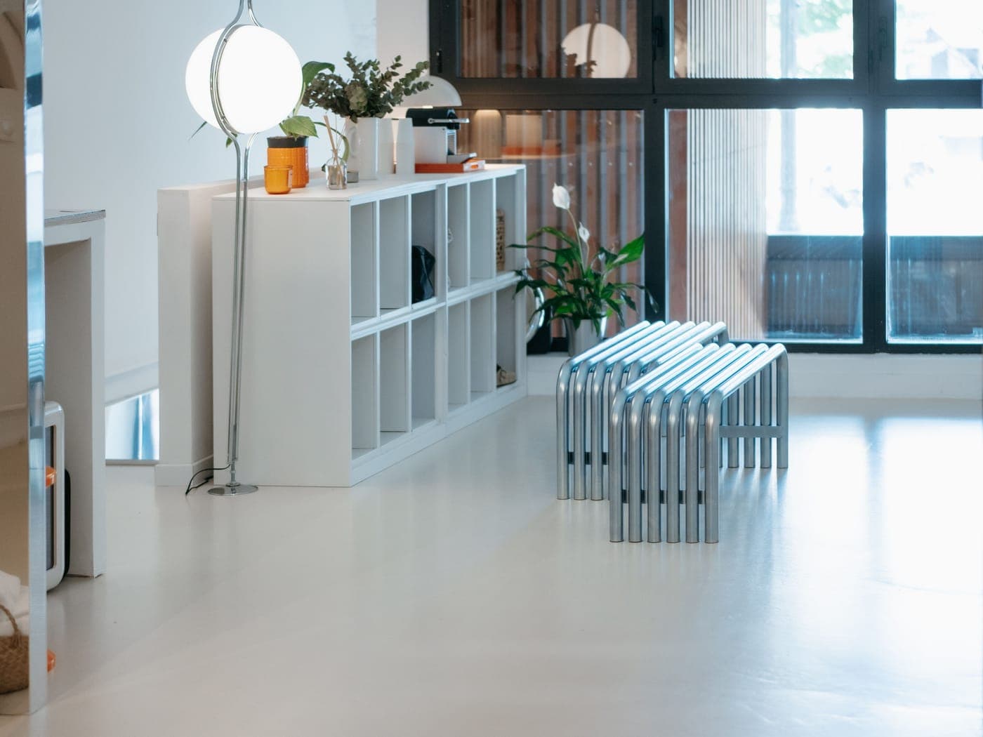 Espace d'accueil du Club Sisko, bibliothèque blanche, lampe globe, bancs en aluminium et grande baie vitrée