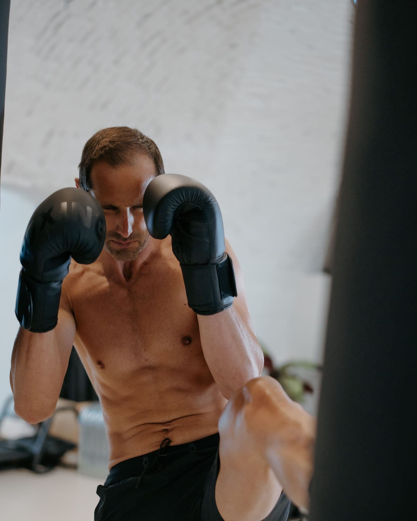Julien, coach du Club Sisko, en garde et montée de genou face au sac de frappe, sous la voûte en briques blanchies