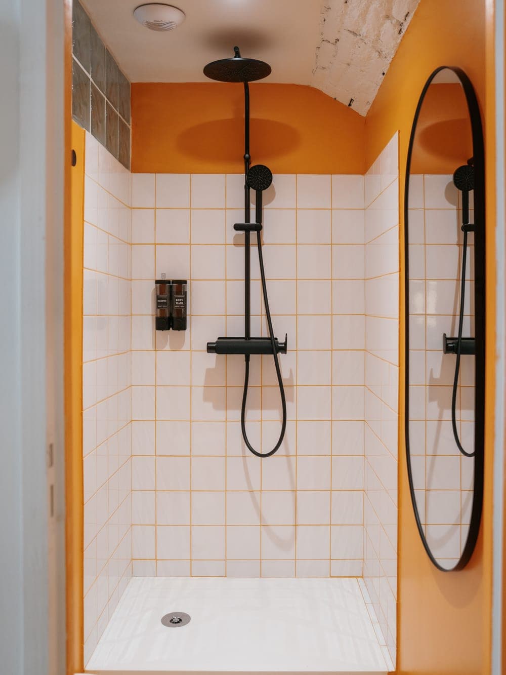 Douche du Club Sisko, carrelage blanc aux joints orangés, murs orange et miroir ovale