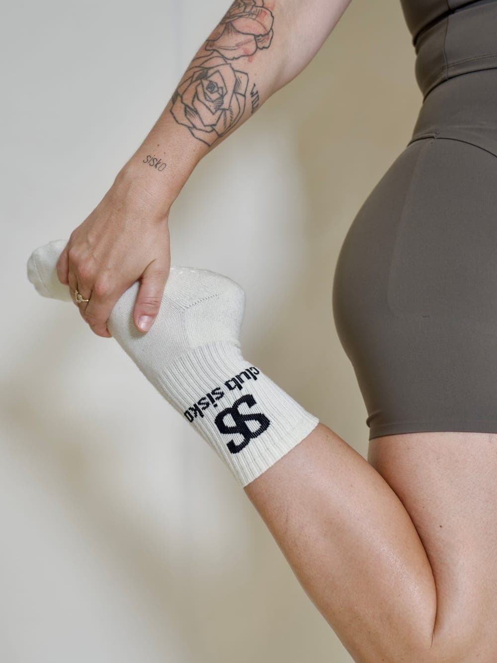 Étirement du quadriceps, chaussette antidérapante Club Sisko tenue à la main