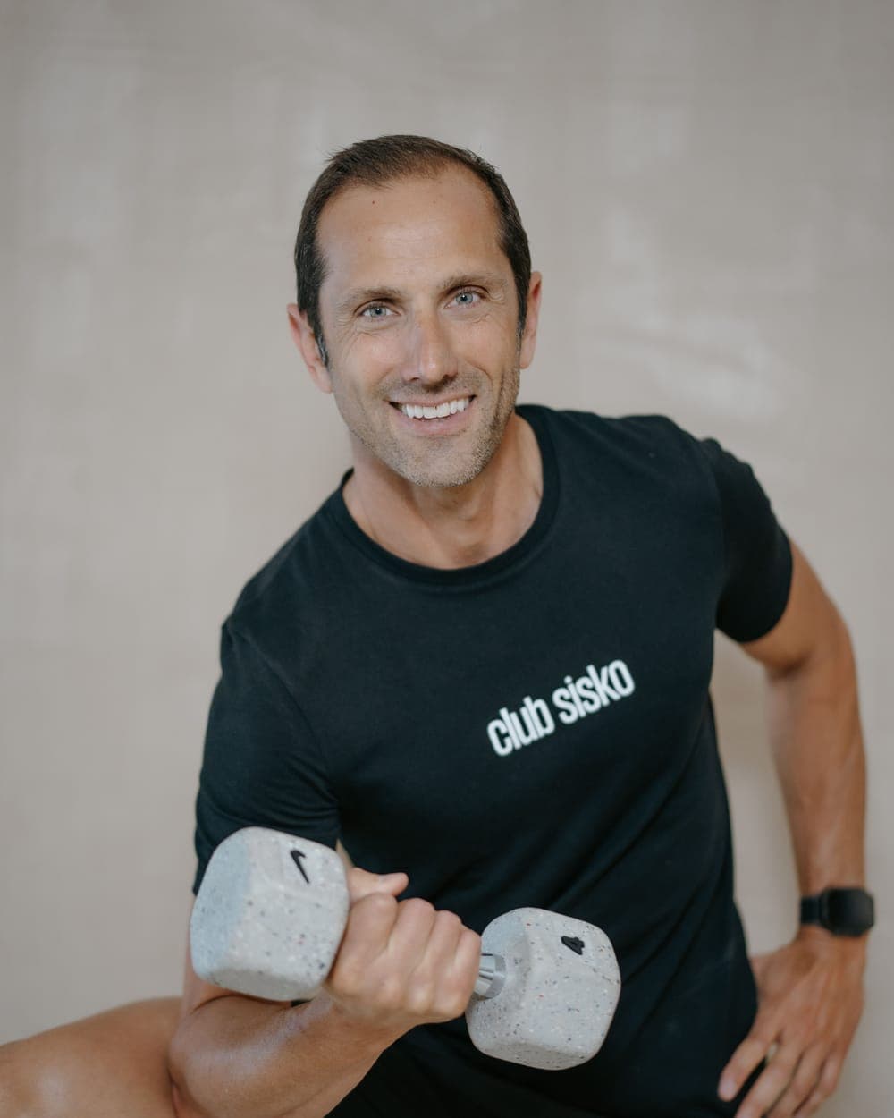Julien, coach du Club Sisko, souriant en t-shirt du club, haltère à la main