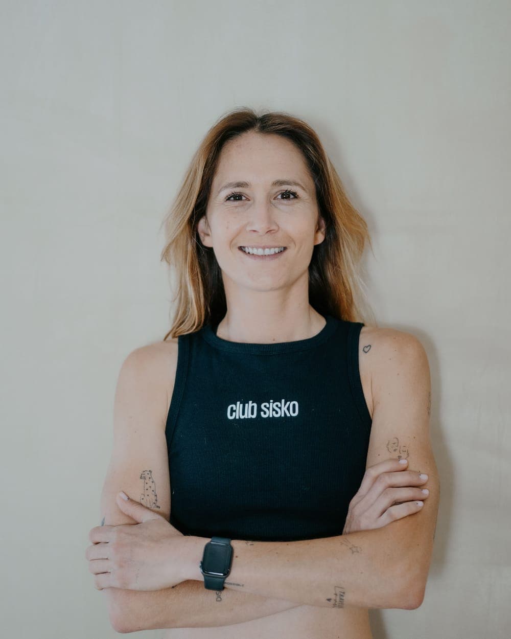 Merryl, coach et cofondatrice du Club Sisko, souriante et bras croisés en débardeur du club