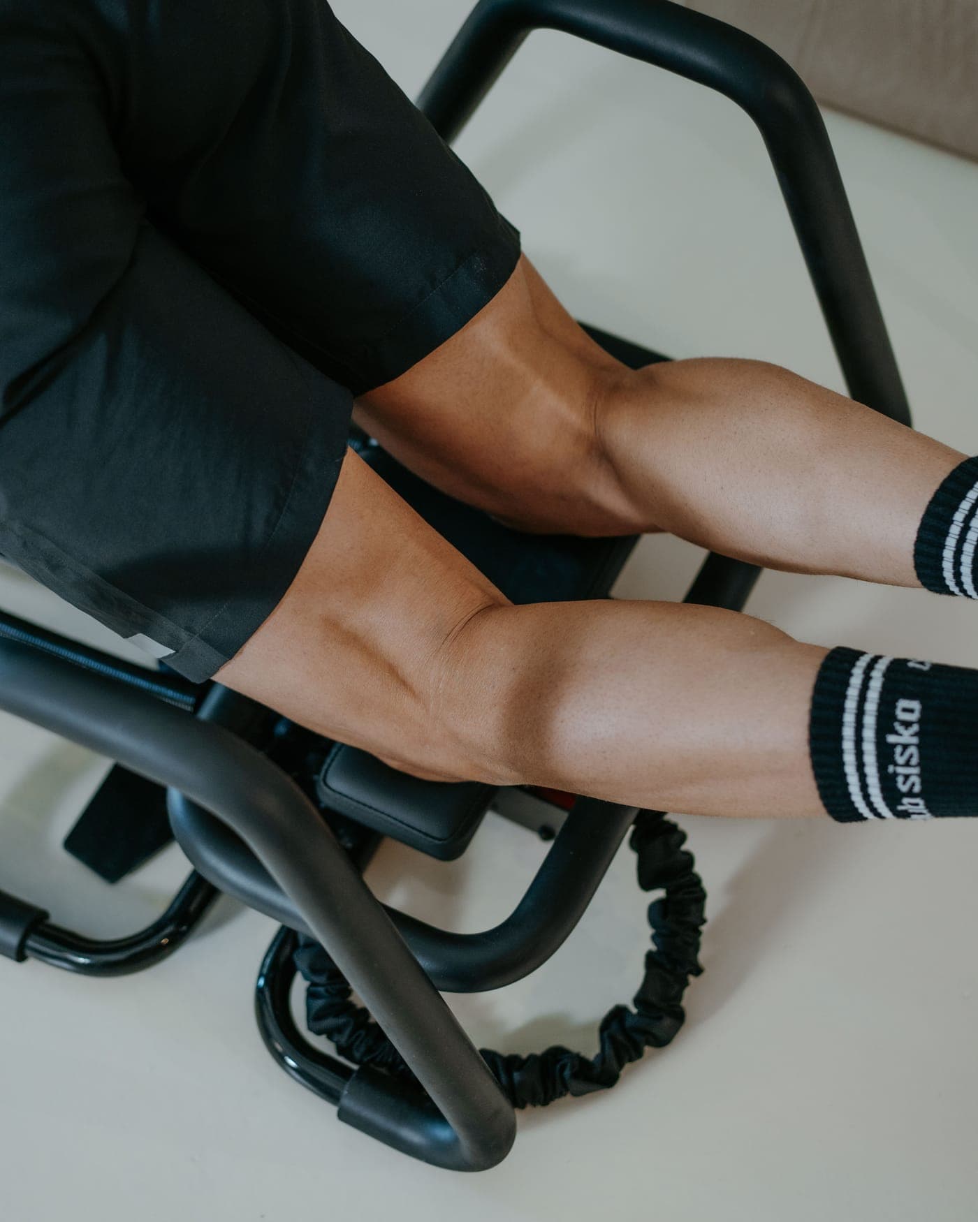 Jambes gainées sur la plateforme d'un Microformer, poignées et câble élastique, chaussettes Club Sisko